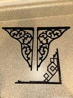 Two matching scrolled brackets and one geometric bracket on countertop