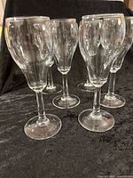 Six clear stemmed champagne glasses on black cloth