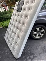 Full Coleman Double QuickBed air mattress leaning against vehicle