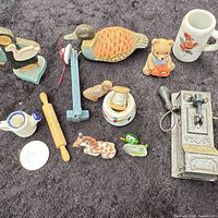 Group shot of all miniature items on dark cloth including rolling pin, mug, pitcher, figurines, jar, grinder
