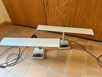 Front view of both off-white desk lamps showing full design and cords