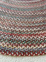 Close view of braided wool rug showing alternating multicolor strands