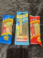 Front view of three sealed Yoda PEZ dispensers: blue bag, blister card, red bag
