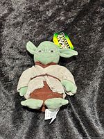 Front view of Yoda plush showing robe, facial details, and hang tag