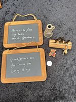Front view of two chalkboard plaques, pewter pitcher, wooden train, mouse and girl figurines with coin for scale
