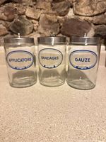 Front view showing three labeled glass apothecary jars with stainless lids