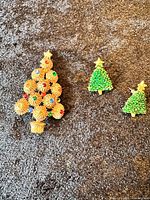 All three Christmas tree brooches on textured background