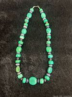 Full view of green malachite, blue lapis and sterling silver beaded necklace laid flat