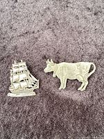 Front view of both pewter pins on fabric background