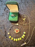 Group shot showing ring in box, Lia Sophia pendant necklace, yellow-green stone choker, floral pin