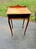 Front view of wooden telephone table showing cabriole legs and open shelf