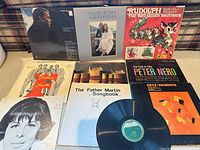 Group shot of all visible album covers and one loose vinyl record.