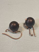 Close-up of both earrings showing gold hooks and black beads