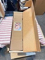Long cardboard box filled edge-to-edge with cards, one sample card on top