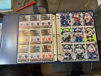 Blue binder open displaying plastic pages with base cards on left, foil insert cards on right