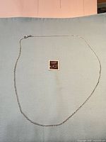 Full view of sterling silver cable chain laid flat with clasp and scale reference