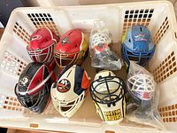 Eight mini NHL goalie mask coin banks inside basket