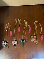 Four pendant necklaces laid out showing motifs and tags