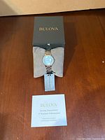 Watch on cushion inside Bulova box with booklet nearby