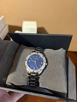 Bulova stainless steel watch on cushion inside box, blue dial visible