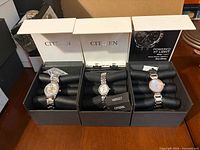 Three boxed wrist watches displayed side by side showing overall lot contents