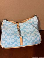 Front view of light blue Coach signature canvas hobo with tan leather trim and silver clip
