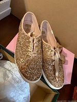 Top view of both glitter sneakers showing ribbon laces and interior labeling