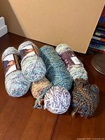 Five partial skeins of Lion Brand Homespun yarn on table showing colors and form