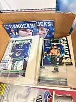 Open box showing several Canucks programs in sleeves, visible Roberto Luongo cover