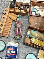 Grouped view of pipes, rack, Coca-Cola tin, Drum tin and assorted cigarette tins in wooden trays
