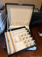 Jewelry box open showing removable tray with ring rolls and compartments