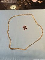 Full view of necklace laid out on fabric with stamp for scale