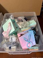 Plastic tote filled with small boxes, bags and jewelry bags