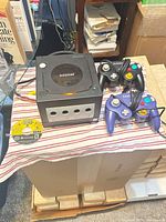 Console, two controllers, game disc and AV cable laid out on striped cloth