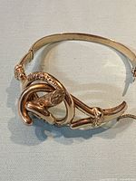 Front view of gold hinged bangle showing knot motif and overall design