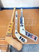 All three mini sticks laid out: wood vintage logo, Trevor Linden #16, Roberto Luongo goalie