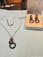 Necklace laid out showing adjustable chain and pendant; earrings in box