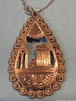 Front view of teardrop pendant showing rose gold filigree and architectural motif
