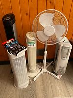 Group shot of five appliances: three tower fans, pedestal fan, oil heater