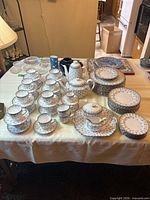 Full set displayed on table including cups, saucers, pots, plates