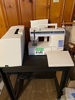 Front view of sewing machine with cover and extension tables