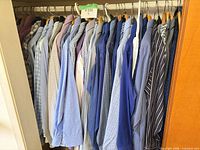 Full closet view of approximately 22 men’s dress shirts on hangers