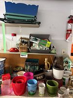 Wide view showing assorted pots, blue metal window boxes, birdhouse and other items on shelves