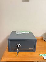 Front view of Sentry Safe V120 showing key in lock and accessory bag on top