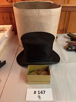Top hat in front of hat box with small box of buttons