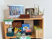 Shelf with aquarium toy, model ship, maze puzzle, card box, assorted boxed games and puzzles