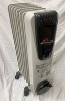 Front three-quarter view of DeLonghi oil-filled radiator heater showing fins and control panel