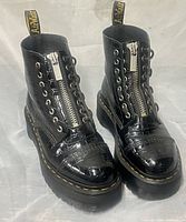 Front view of both boots showing zipper, laces, patent croc texture