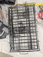 Folded black metal dog crate with adjacent grey fabric pet carrier corner visible