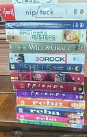 Stack of 13 DVD box sets showing spines with series titles and seasons